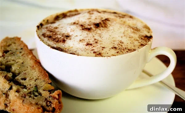 A beautifully presented cup of homemade chai tea next to a homemade biscotti, inviting a moment of relaxation.