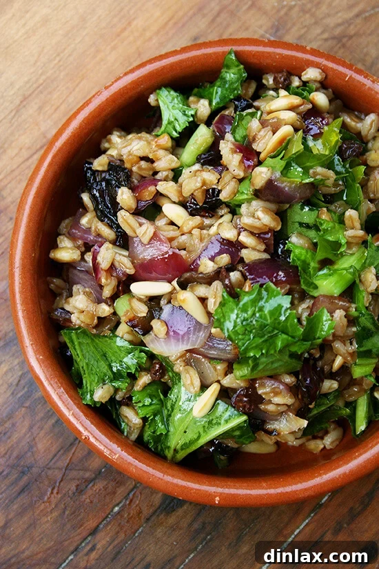 A vibrant bowl of farro salad, showcasing roasted onions, perfectly toasted pine nuts, and tender, wilted mustard greens. A healthy and delicious meal.