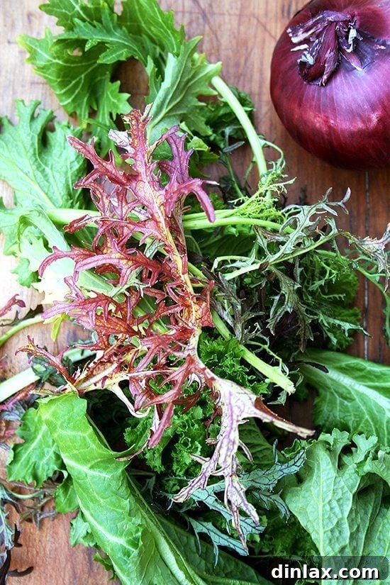 A vibrant mix of Asian greens, including various mustard varieties, freshly harvested from a CSA delivery.