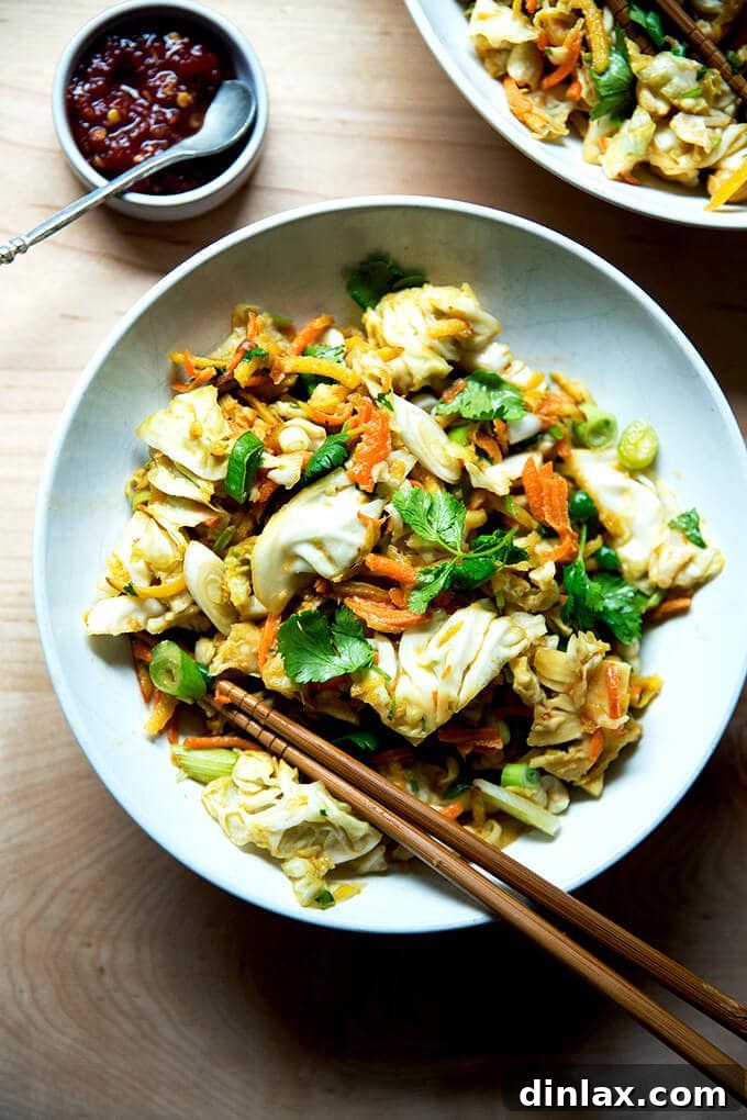 A beautifully presented bowl of chopped Thai satay salad, garnished and ready to be enjoyed, with a small dish of hot sauce alongside.