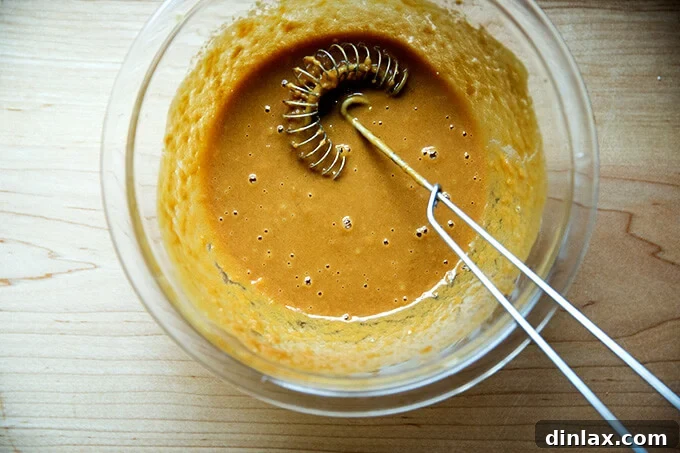 The fully mixed, smooth, and creamy Thai peanut-ginger dressing in a bowl, ready to be poured over the salad.