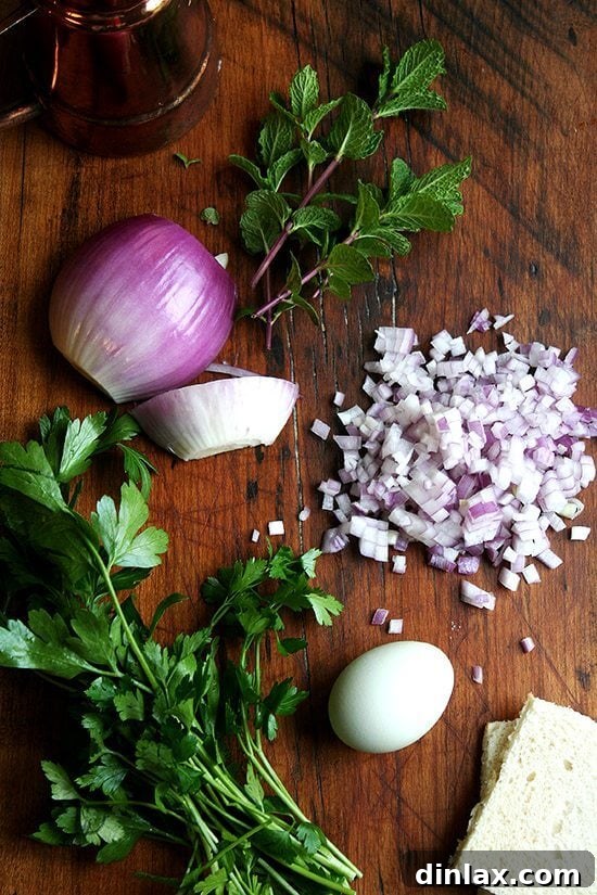 Fresh ingredients: mint and diced red onion for lamb keftedes A wooden cutting board with fresh mint leaves and finely diced red onion, essential ingredients for the lamb meatballs.