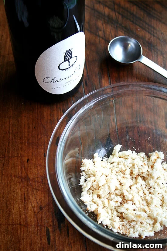 Red wine and soaked bread for meatballs A bowl of crumbled, wine-soaked bread sits beside a bottle of red wine, highlighting a key ingredient for moist meatballs.