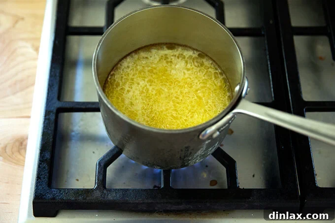 The Art of Ghee Making: A Home Kitchen Guide 5 Butter vigorously bubbling in a saucepan, with foam on top and subtle browning beginning around the edges.