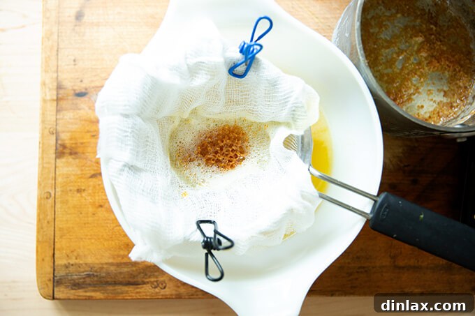 The Art of Ghee Making: A Home Kitchen Guide 6 Carefully straining freshly cooked ghee through multiple layers of cheesecloth into a glass bowl.