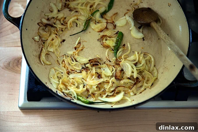 Perfectly sautéed onions, caramelized to a golden brown, and softened chilies in the braiser pan, ready to be added to the rice.