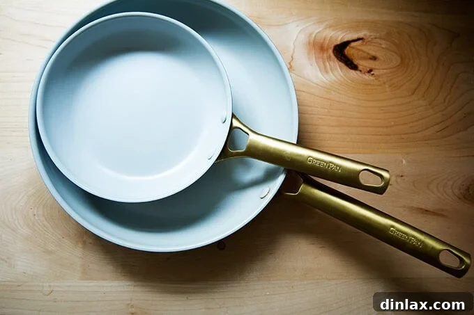 Two sleek Food52's Greenpan nonstick skillets, an 8-inch and an 11-inch, on a kitchen surface.