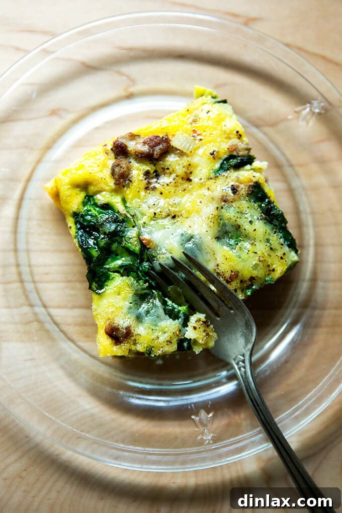 A delicious slice of sausage, spinach, egg, and Gruyère cheese breakfast casserole, ready to be served for a festive brunch or hearty breakfast.