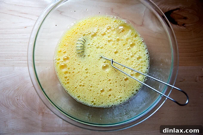 The twelve eggs, thoroughly whisked with half-and-half and seasoning, creating a smooth and airy mixture.