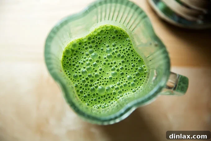 A blender filled with green smoothie, finished blending, showing the vibrant green color.