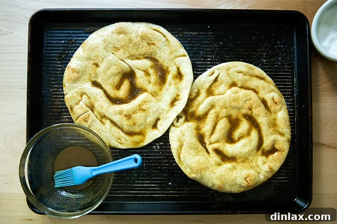 Vibrant Spring Fattoush 5 Two rounds of pita bread brushed with olive oil, cumin, and salt, ready for baking on a sheet pan.