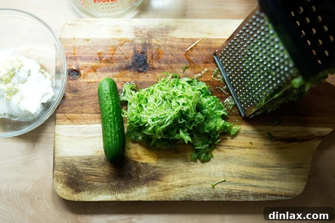A cutting board with a mound of freshly grated cucumber, the key ingredient for the cool and refreshing cucumber-yogurt sauce.