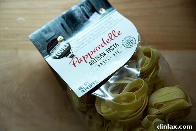 A bag of dried pappardelle pasta, showcasing its wide, flat ribbons, awaiting cooking.
