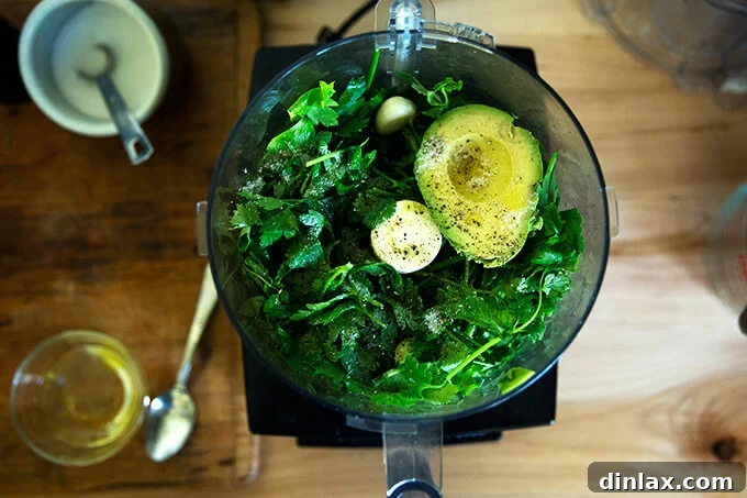 The Ultimate Herby Avocado Green Sauce 4 A food processor filled with the green sauce ingredients, ready to be blended.