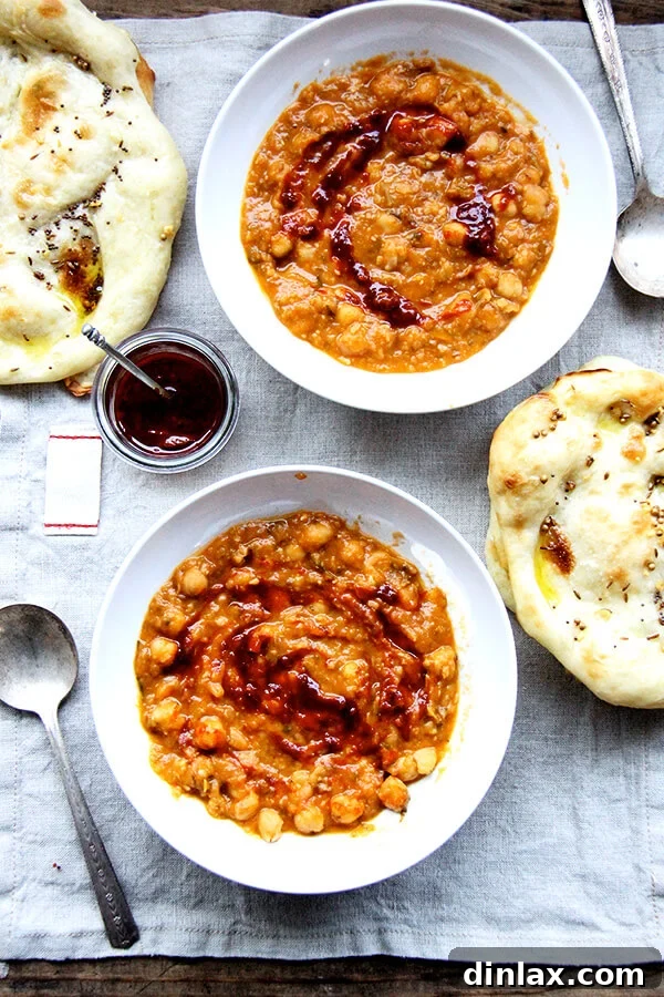 Two bowls of Leblebi, a hearty Moroccan chickpea soup, garnished with various toppings like bread, eggs, and herbs, inviting a rich cultural culinary experience.