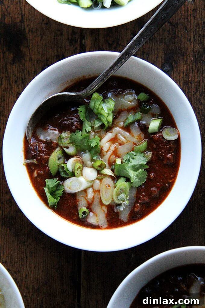 A steaming bowl of rich weeknight chili, garnished with a dollop of sour cream or cheese, suggesting a warm and satisfying meal for any occasion.