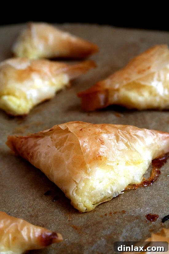 A sheet pan filled with golden-baked Tiropitas, fresh out of the oven and ready to be enjoyed.