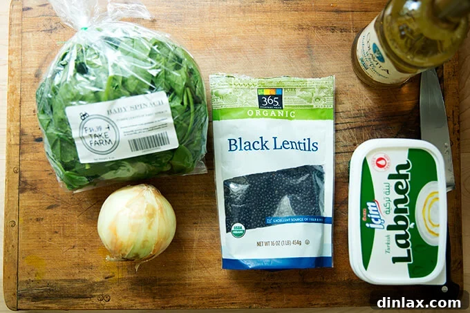 Irresistible Black Lentil and Spinach Delight 5 A cutting board with ingredients for black lentils and spinach: lentils, onion, spinach, balsamic vinegar.