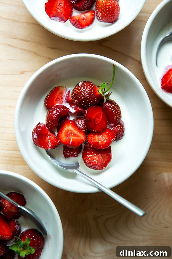 A vibrant bowl of fresh, ripe strawberries perfectly complemented by a generous dollop of rich, chilled cream, symbolizing the pure joy of summer's first harvest.