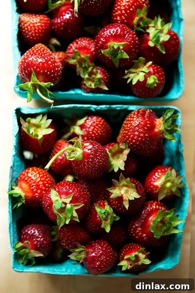 Close-up of fresh, local strawberries neatly arranged in their market cartons, promising a delicious transformation into a beloved summer dessert.