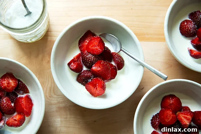Four bowls of strawberries and cream, now delicately dusted with a fine layer of sugar, perfectly poised for immediate enjoyment and a burst of flavor.