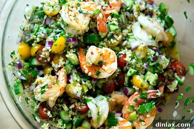 A close-up of a bowl of Tabbouleh, now mixed with succulent grilled shrimp, fresh cilantro, and lime.