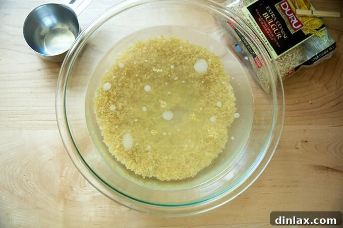 Bulgur grains gently soaking in a bowl of cold water, preparing for hydration.