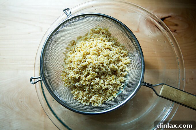 Soaked bulgur, fully drained through a sieve, ready to be combined with fresh ingredients.