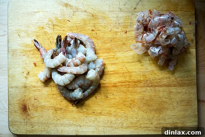 Peeled raw shrimp arranged on a cutting board, ready for the next preparation step.