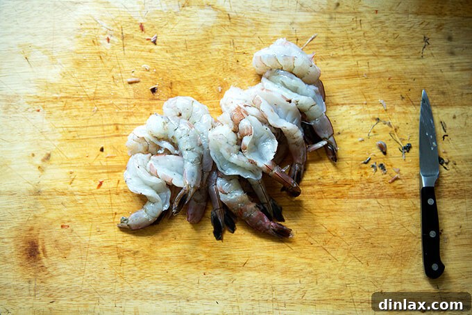 Butterflied raw shrimp on a cutting board, prepped and ready for grilling.