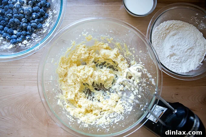 An overhead shot of a handheld mixer creaming butter and sugar in a bowl until light and fluffy.
