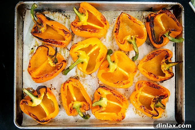 Hearty Harvest Stuffed Bell Peppers 12 A sheet pan displaying blistered orange bell peppers, now flipped cut-side up, forming perfect vessels for the delicious filling.
