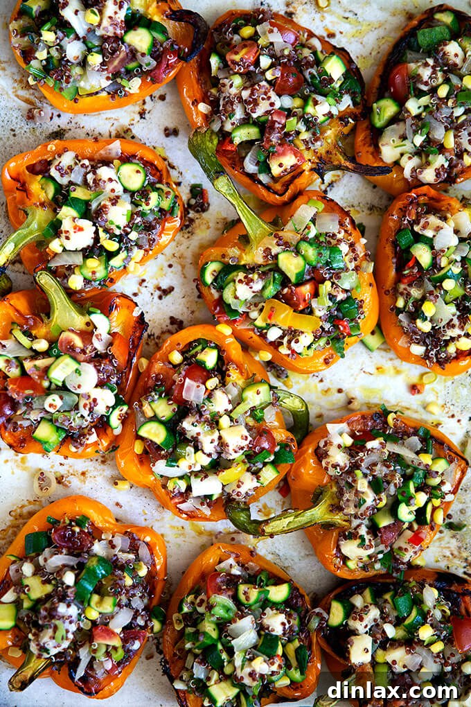 Hearty Harvest Stuffed Bell Peppers 13 A baking sheet showcasing orange bell peppers, beautifully stuffed with a hearty mixture of quinoa, fresh vegetables, and creamy Monterey Jack cheese, ready to be baked to perfection.