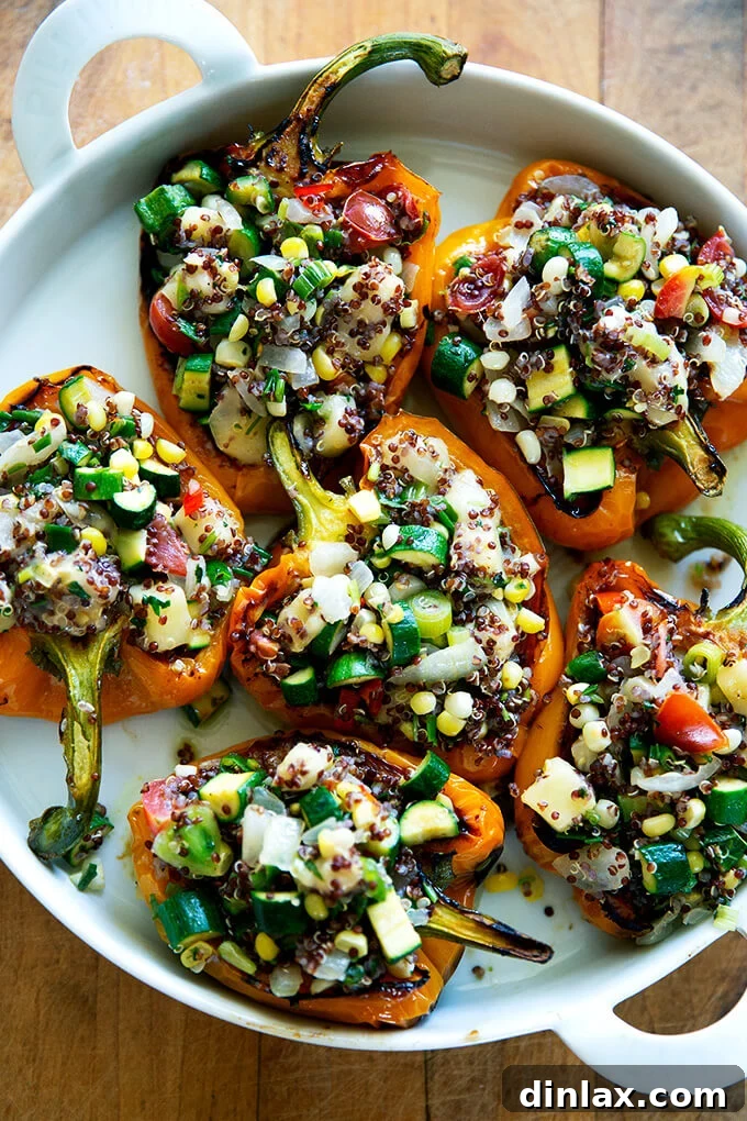 Hearty Harvest Stuffed Bell Peppers 14 A round white dish proudly presenting several orange bell peppers, beautifully stuffed with a savory blend of quinoa, summer vegetables, and melted Monterey Jack cheese, fresh from the oven.