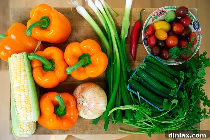 Hearty Harvest Stuffed Bell Peppers 3 A vibrant collection of fresh ingredients laid out on a wooden cutting board, featuring bright orange bell peppers, a whole onion, green scallions, fresh zucchini, ripe tomatoes, and fragrant cilantro, ready for preparation.
