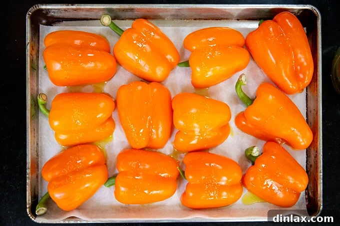 Hearty Harvest Stuffed Bell Peppers 4 A baking sheet filled with orange bell peppers, halved and cored, placed cut-side down, glistening with olive oil and ready for roasting.