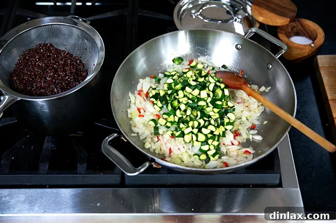 Hearty Harvest Stuffed Bell Peppers 6 A sauté pan filled with a colorful mix of gently cooked onions, chili, and tender diced zucchini, showcasing the fresh ingredients being prepared for the pepper filling.