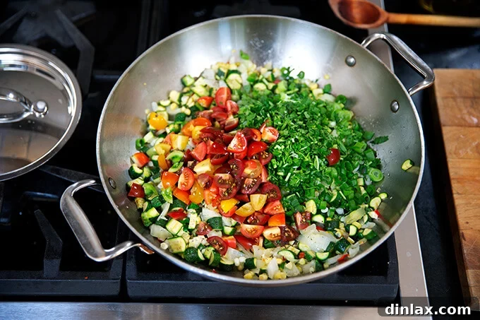 Hearty Harvest Stuffed Bell Peppers 8 A sauté pan generously filled with a vibrant mix of sautéed onions, chili, zucchini, corn, and fresh tomatoes, all brightened by the addition of fragrant herbs like scallions and cilantro.