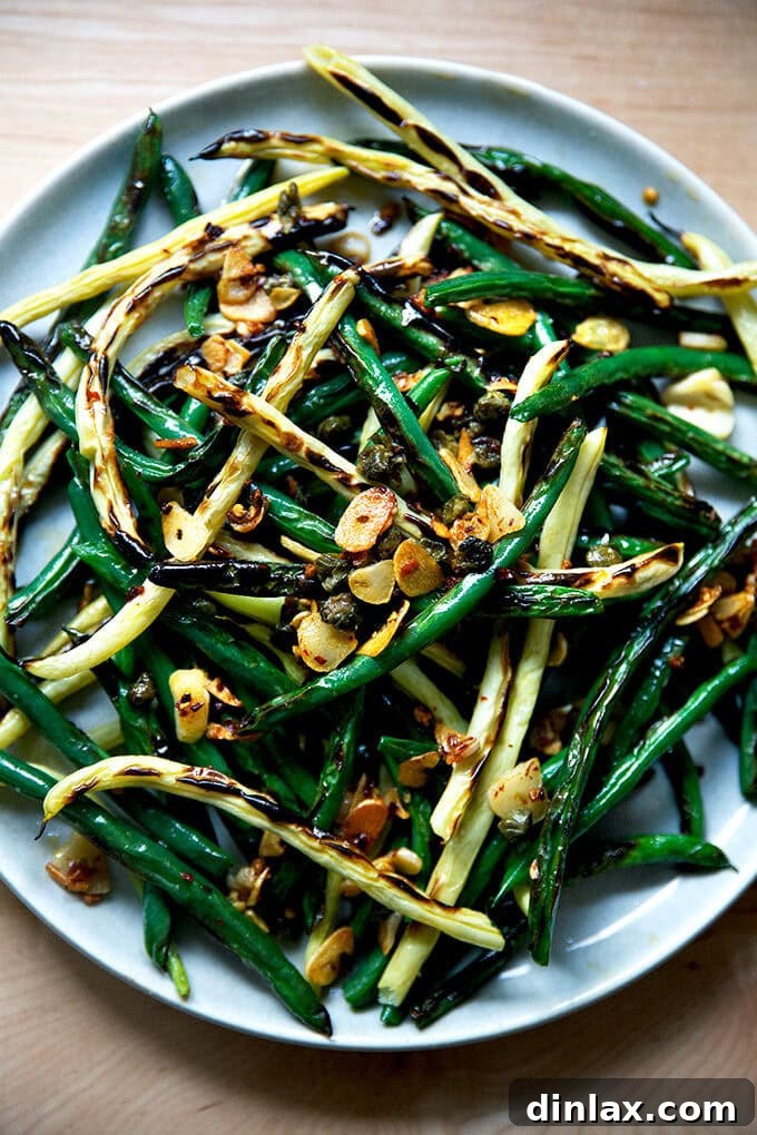 Blistered fresh green beans on a platter, ready to be served. The beans have a beautiful char and are glistening with oil.