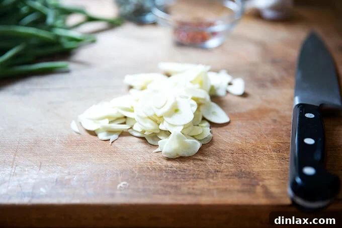 Thinly sliced garlic cloves neatly arranged on a cutting board, ready for infusion.