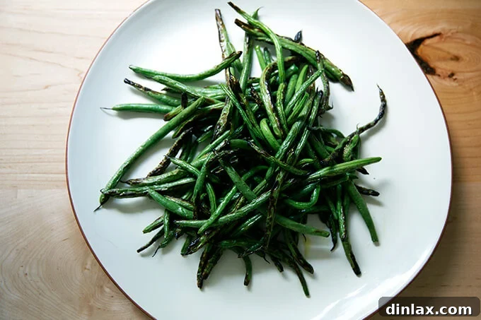A platter brimming with beautifully blistered green beans, displaying their perfect char and vibrant green color.