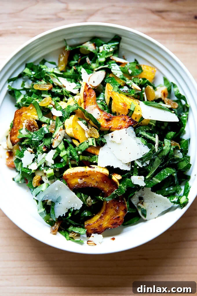 A bowl of vibrant collard greens salad with perfectly roasted delicata squash, golden raisins, shaved Parmesan, and crunchy toasted almonds, ready to be enjoyed.