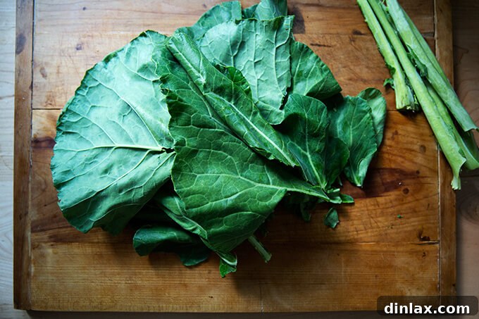 Cleaned collard greens, with tough stems meticulously removed, arranged neatly on a wooden board.