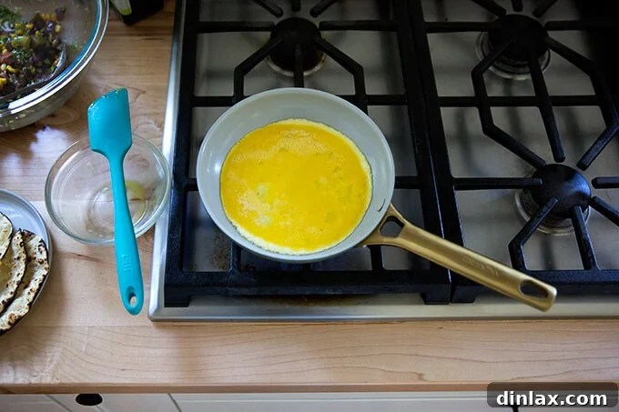 An 8-inch nonstick skillet gently cooking two eggs, perfectly prepared for breakfast tacos.