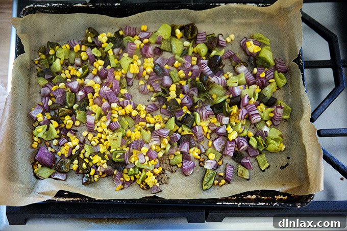 Beautifully roasted vegetables, showing charring and caramelization, on a sheet pan lined with parchment paper.