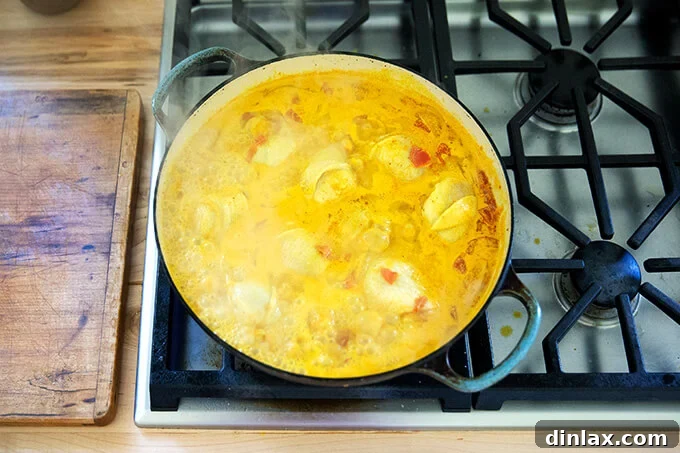 A sauté pan with curry sauce and chicken.