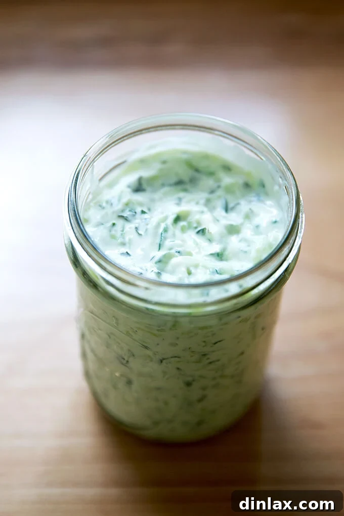 Homemade tzatziki stored neatly in a clear glass jar, showcasing its fresh and inviting appearance, ready for refrigeration.