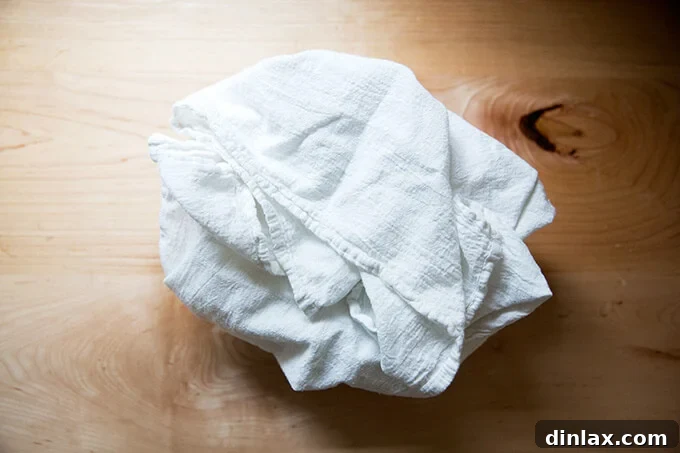 A bowl, lined with a tea towel, filled with a round of sourdough.