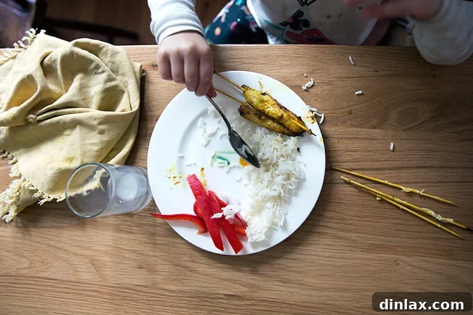 My daughter, Tig, beams with delight as she savors her easy Thai chicken satay and coconut rice, demonstrating the dish's kid-friendly appeal.