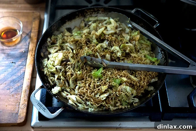 A large sauté pan filled with fully cooked mushrooms, cabbage, ramen noodles, and scallions, tossed in a savory ginger-scallion sauce.